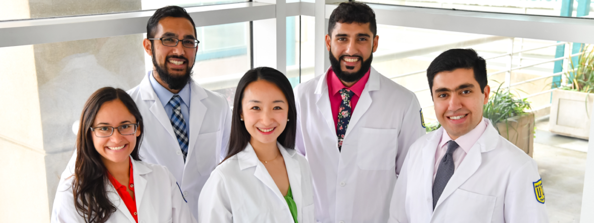 Five medical professionals smiling in white coats.