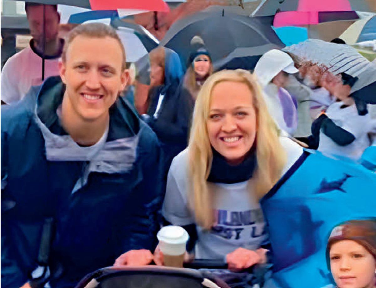 Smiling couple with a stroller in the rain.