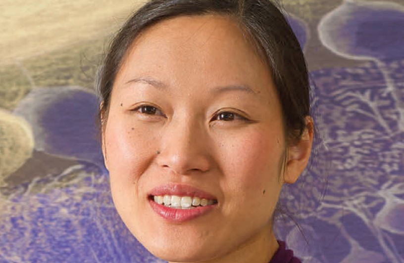 A woman smiling in front of a colorful background.