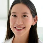 Smiling woman with long dark hair in a white shirt.