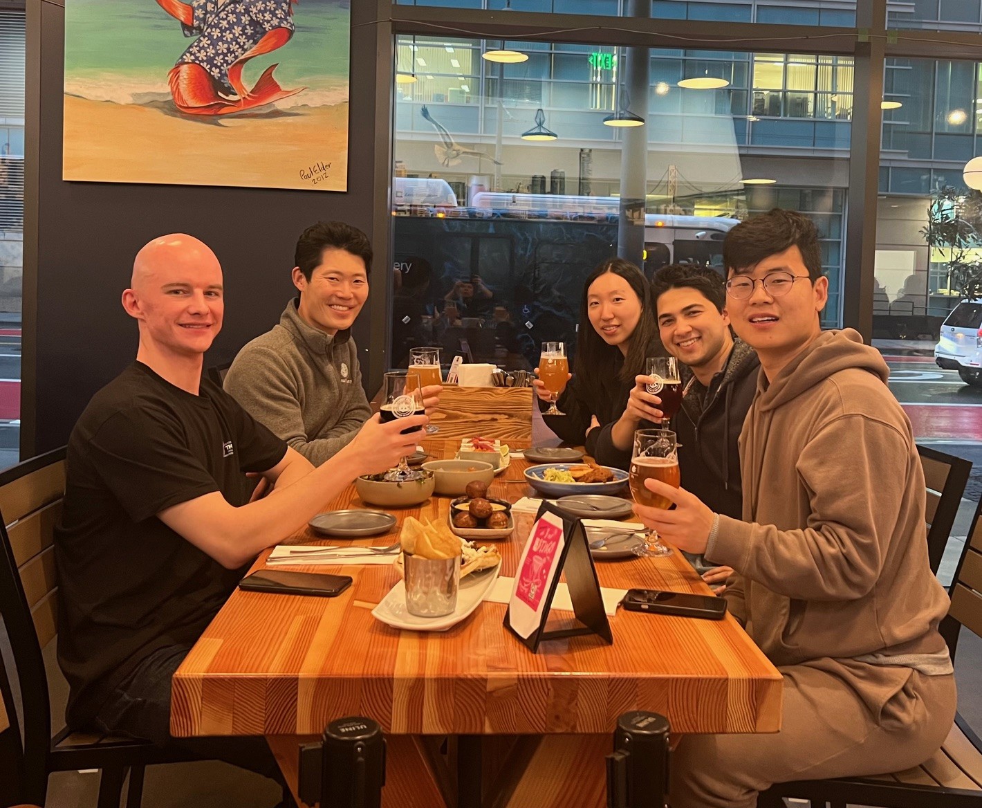 Group of five friends enjoying drinks at a restaurant.