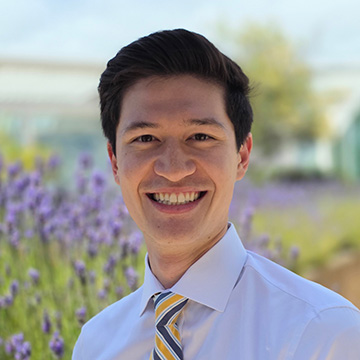 Smiling man in a light shirt among lavender flowers.
