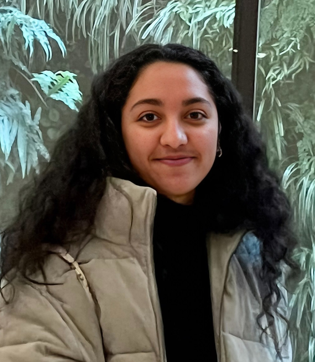 Person smiling in a light jacket with foliage background. Ou Lab Research People UCSF Yvonne.