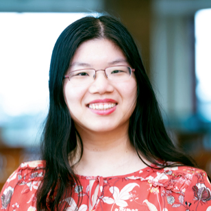 Smiling woman with long black hair wearing glasses and a floral blouse.