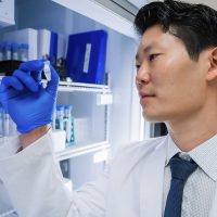 Scientist examining a vial in laboratory.
