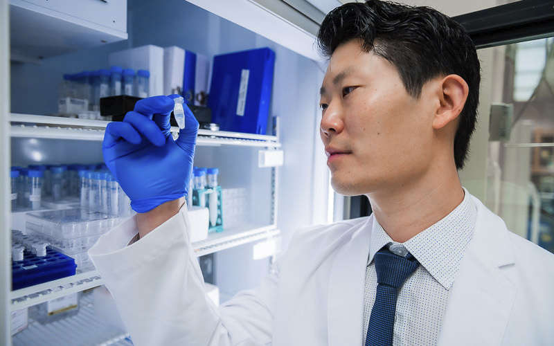 Scientist examining a vial in laboratory.