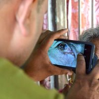 Person photographing elderly woman's eye.