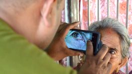 Person photographing elderly woman's eye.