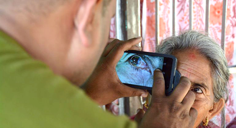 Person photographing elderly woman's eye.